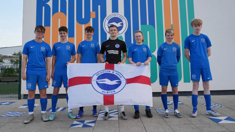 Seven BHAFC Foundation disability football players hold a Brighton & Hove Albion flag after England Para Talent Pathway call-ups. Image: BHAFC Foundation